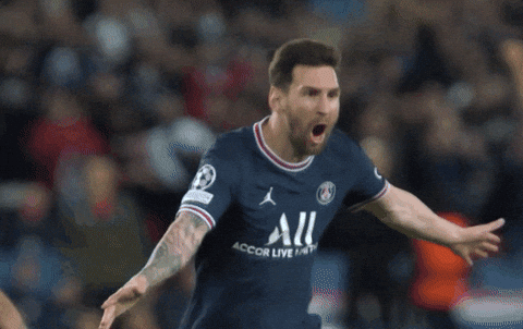 Lionel Messi, vistiendo la camiseta del PSG, celebra un gol con los brazos abiertos y una expresión de emoción intensa, corriendo por el campo de fútbol mientras su rostro refleja euforia.